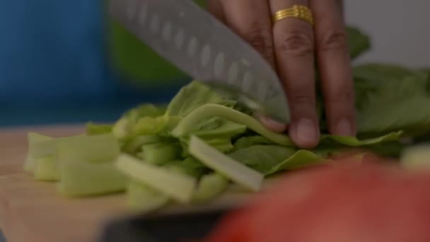 台所でテーブルの上に健康的な食品のための木製のまな板の上に中国のキャベツを切断女性の手のショットを閉じます — ストック動画