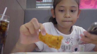 Yemekte cep telefonu kullanırken yemek yiyen Asyalı tatlı kız..