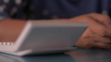 Evdeki masada akıllı telefon kullanan bir kadın cep telefonuna mesaj yazıyor. Evden çalış..