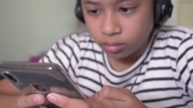 Evde kulaklıkla akıllı telefondan video izleyen sevimli Asyalı kız..