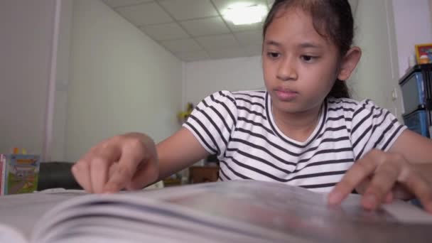 机の上で本を読んでいる可愛いアジア系の女の子 教育理念 — ストック動画