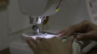 Kadın elleri COVID-19 salgını sırasında evde dikiş makinesiyle koruyucu yüz maskesi dikiyor. Yeniden kullanılabilir yüz maskesi. Evden çalış..
