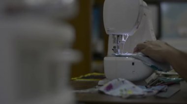 Ev hanımı COVID-19 salgını sırasında evde dikiş makinesiyle koruyucu yüz maskesi dikiyor. Yeniden kullanılabilir yüz maskesi. Evden çalış..