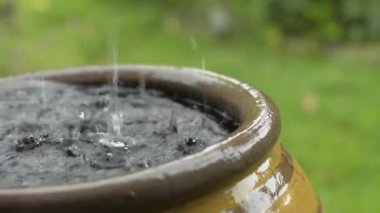 Çamur kavanozuna düşen yağmuru kapat. Sığ alan derinliğine sahip seçici odak.