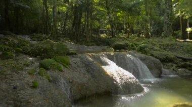 Şelaleden akan su akıntısının muhteşem manzarası tropikal yağmur ormanlarındaki güneş ışığı altındaki küçük doğal bir gölete. Döndürme atışı. Sa Nang Manora orman parkı. Phang Nga Eyaleti. Tayland