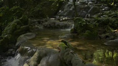 Yazın, tropikal yağmur ormanlarındaki kayaların üzerinden akan su akıntısının muhteşem manzarası. Sa Nang Manora orman parkı. Phang Nga Eyaleti. Tayland.