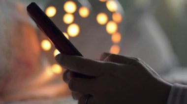 Kadınların ellerini kapat. Akıllı telefondan iletişim kurmak ve geceleri yatak odasında çevrimiçi sosyal medyada sohbet etmek için mesaj at. Modern yaşam için dijital aygıt.