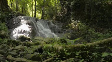 Bereketli bitki örtüsü arasında kayaların arasından akan şelale manzarası. Yaz boyunca tropikal ormanlardaki çağlayanlardan tatlı su akışı sağlanır. Sa Nang Manora Orman Parkı. Tayland.