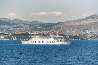 Split, Croatia  July 16, 2019 - Jadrolinija ferry Marjan sails the Adriatic Sea with the Dalmatian coastline and Mosor mountains in the background