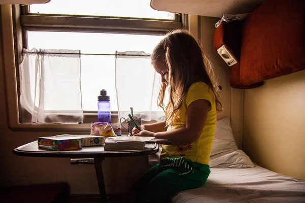 Little girls drawing on the deck in train travelling with family, Russia