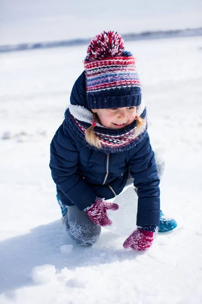 Маленькая улыбающаяся девочка в зимней одежде со льдом и снегом вокруг — стоковое фото