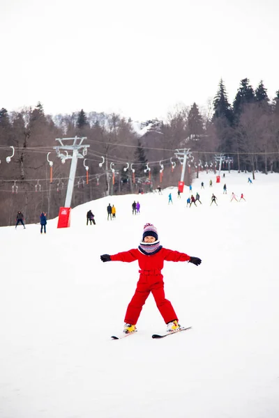 Маленькая улыбающаяся девочка в красном лыжном спорте — стоковое фото