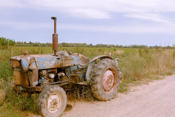 Rusty old tractor machine on roadside of rural remote countryside in cloudy day