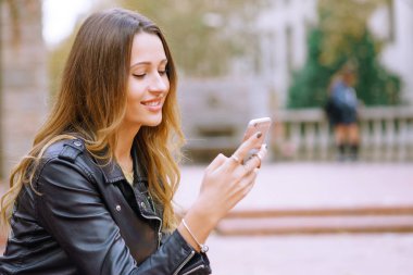 Yan görünüm portre mutlu kadınların akıllı telefon açık havada kullanma