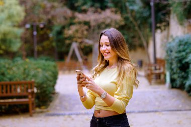 Neşeli Bayan parkta Smartphone kullanarak