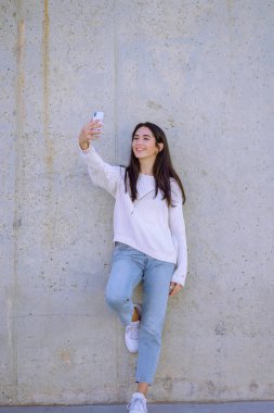Selfie mania! Heyecanlı genç kız bir fotoğraf ile smartphone yapıyor. Açık havada - görüntü