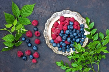   Sulu ve taze yaban mersini ve ahududu koyu arka plan üzerinde yeşil yaprakları ile kopya alanı ile üstten görünüm