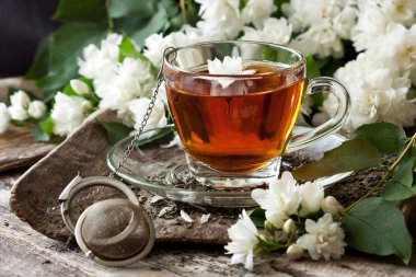 Çay bardağı ile ahşap arka plan üzerinde Yasemin çiçekleri. Seçici odak, fiel sığ derinliği