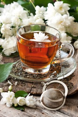 Çay bardağı ile ahşap arka plan üzerinde Yasemin çiçekleri. Seçici odak, fiel sığ derinliği