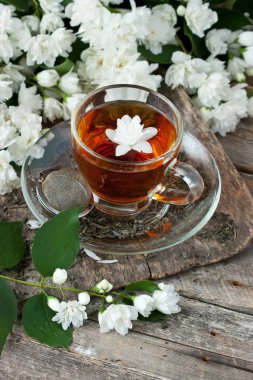 Çay bardağı ile ahşap arka plan üzerinde Yasemin çiçekleri. Seçici odak, sığ derinlik-in tarla