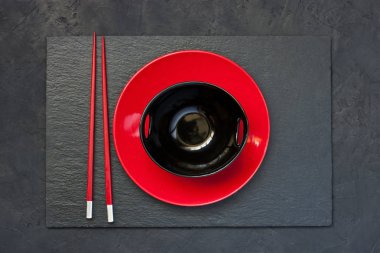 Boş siyah ve kırmızı kase ve beton zemin, üstten görünüm üzerine ahşap çubuk