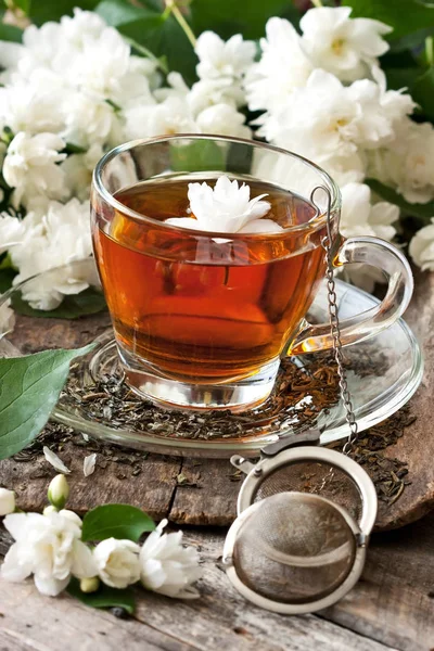 Çay bardağı ile ahşap arka plan üzerinde Yasemin çiçekleri. Seçici odak, fiel sığ derinliği