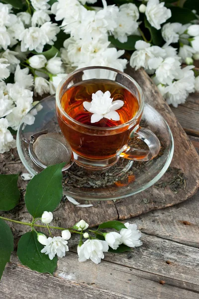 Çay bardağı ile ahşap arka plan üzerinde Yasemin çiçekleri. Seçici odak, sığ derinlik-in tarla