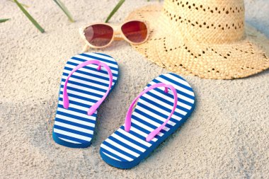 Yaz moda aksesuarları ile saman hasır şapka, terlik ve plaj kum zemin üzerine güneş gözlüğü