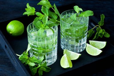 İki bardak Mojito taze limon ve nane siyah tepsi ile kokteyl. Seçici odak alan sığ derinliği ile