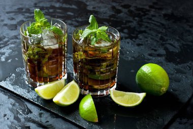 Cuba libre kokteyl limon ve nane cam siyah tepsi ile. Seçici odak alan sığ derinliği ile