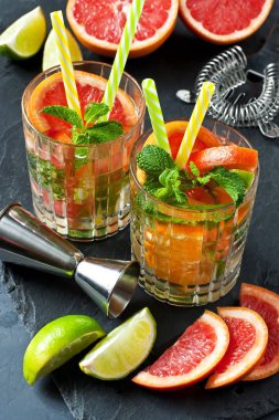 Koyu beton arka planda limon, portakal, greyfurt ve nane yapraklarıyla taze içecek, seçici odaklanma,