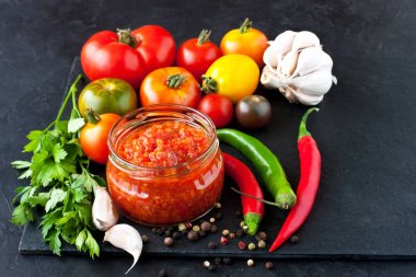 Cam kavanoz, taze domates, maydanoz ve baharat koyu arka plan üzerine domates sosu