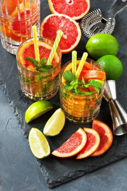 Koyu beton arka planda limon, portakal, greyfurt ve nane yapraklarıyla taze içecek, seçici odaklanma