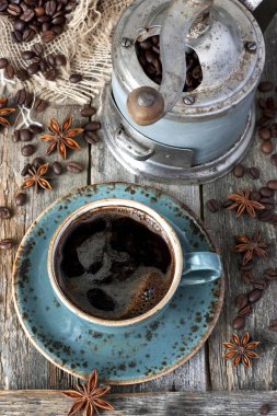 Fincan kahve çekirdekleri ve eski kahve değirmeni ahşap masa üzerinde dolu