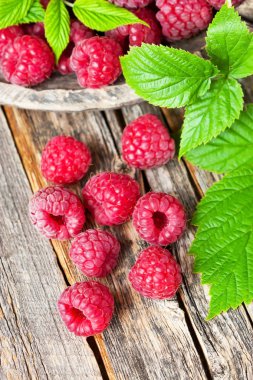 Organik ahududu koyu arka plan, üstten görünüm üzerinde yeşil yaprakları ile. Sağlıklı beslenme antioksidan beslenme kavramı. 