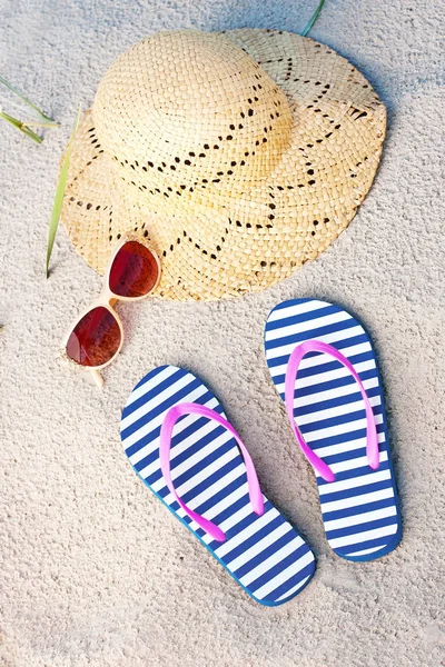 Yaz moda aksesuarları ile saman hasır şapka, terlik ve plaj kum zemin üzerine güneş gözlüğü