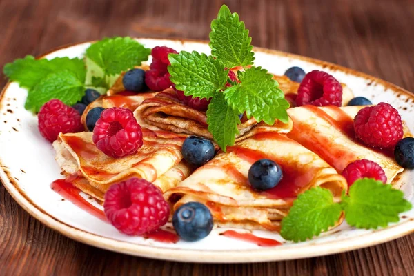 Golden crepes with   raspberry and blueberry. Traditional crepes for pancake week