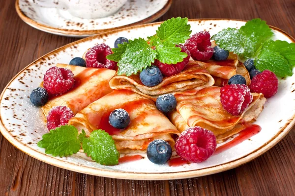 Golden crepes with   raspberry and blueberry. Traditional crepes for pancake week