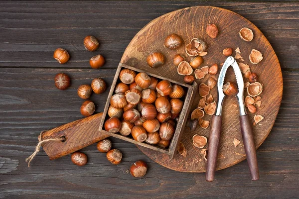 Haselnuss mit Nussknacker auf Holzbrett. Ansicht von oben — Stockfoto