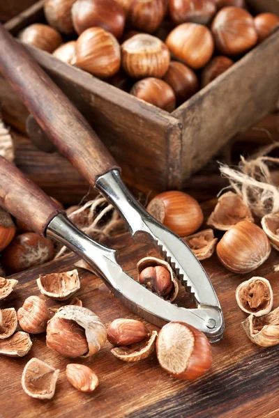 Haselnüsse auf Holzbrett mit Nussknacker häufen — Stockfoto