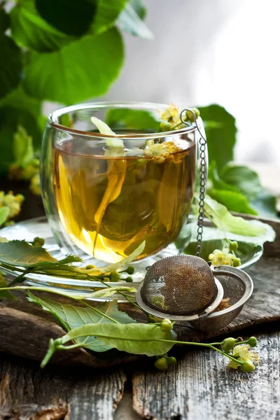 Kopje Linden thee en bloemen op houten tafel — Stockfoto