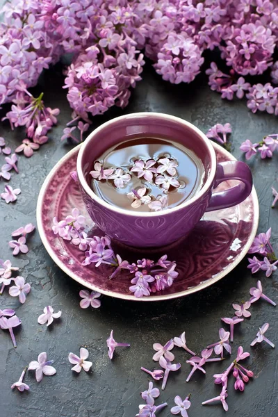 Tazza di tè e lilla sul tavolo scuro — Foto Stock