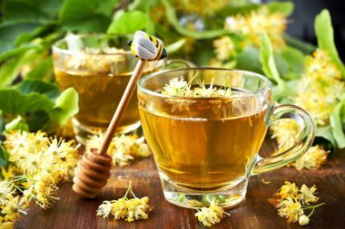 Cup of herbal tea with linden flowers on  old wooden table clipart