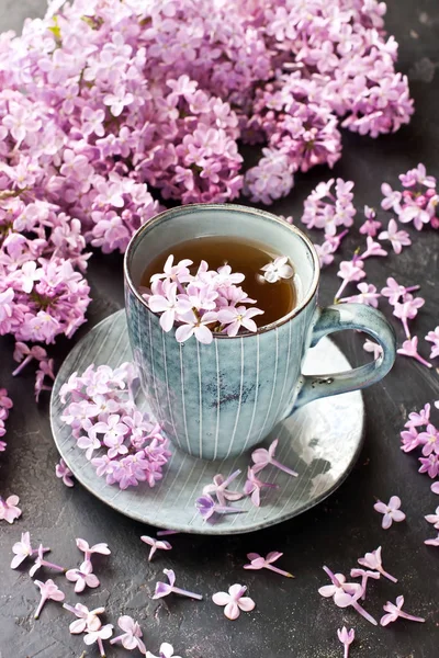 Bodegón con taza de té y lila sobre fondo oscuro —  Fotos de Stock
