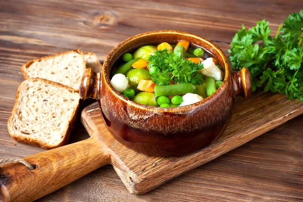 Keramiktasse mit Gemüsesuppe auf rustikalem Holzgrund — Stockfoto