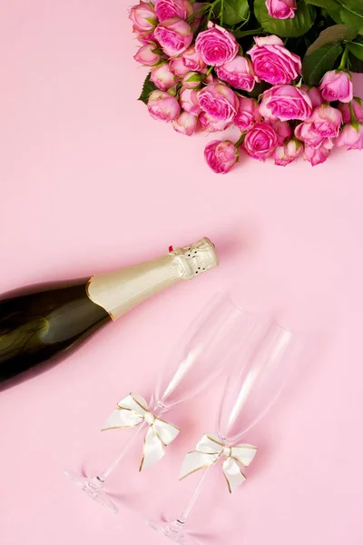 Två spottar champagneglas med rosor bukett över färg bakgrund — Stockfoto