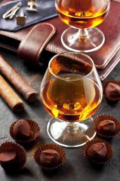 Koyu masada bir bardak viski, çikolatalı yer mantarı ve puro