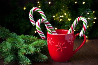 Kırmızı ve yeşil çizgili nane şekeri kamışları Noel bardağında ahşap masada.