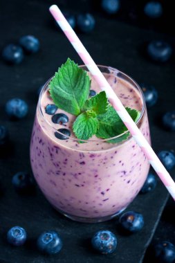 Koyu arka planda nane yaprakları ile cam yaban mersini smoothie