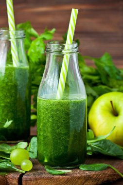 Ispanak, salatalık ve elmalarla dolu yeşil detoks smoothie ve koyu rustik ahşap arka planda saman